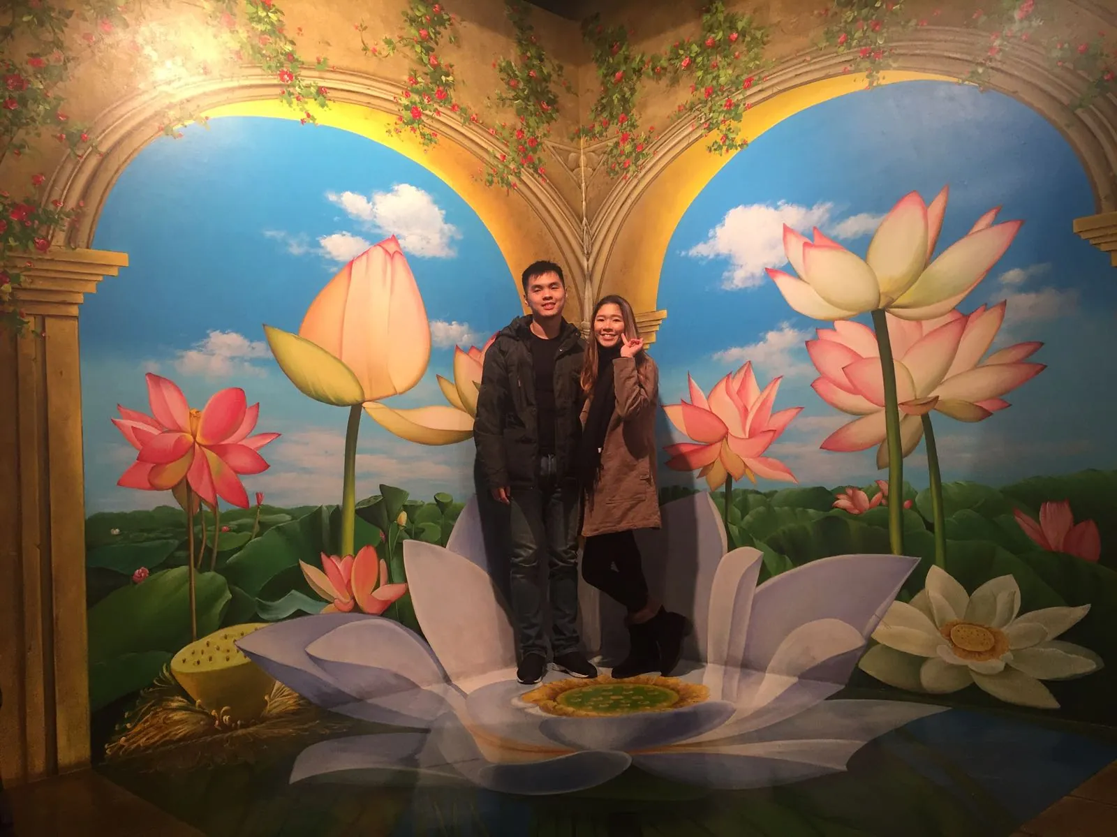 Nicholas and his wife posing in a lotus flower illusion at Trickeye Museum
