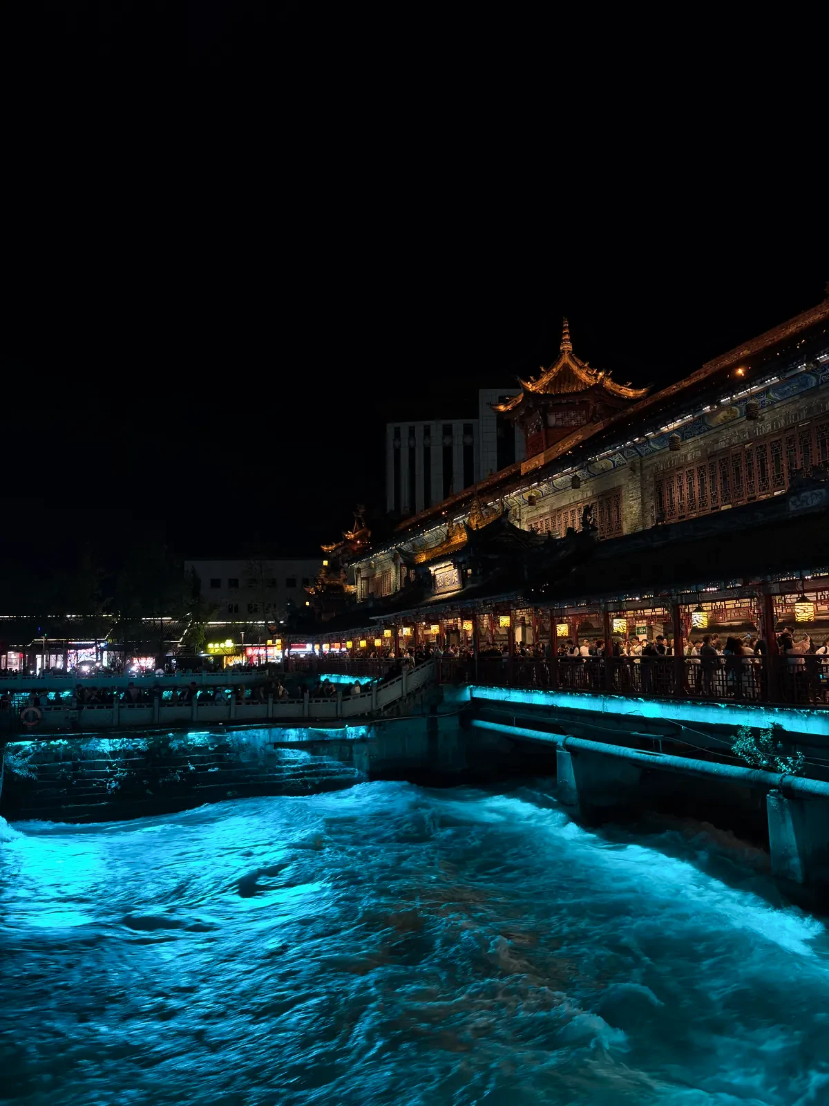 Blue-lit water flowing beneath South Bridge in Dujiangyan at night