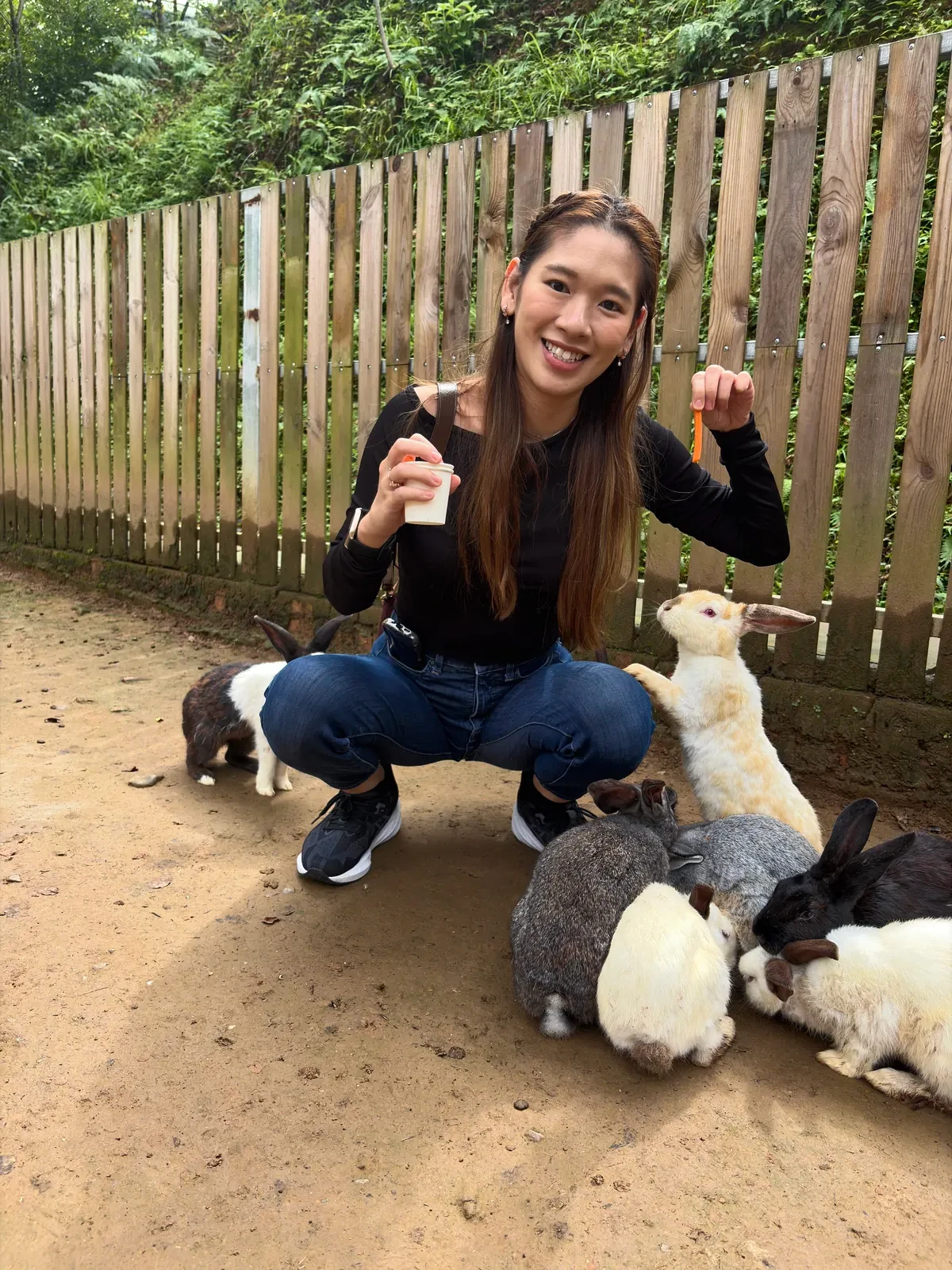 Woman crouching beside rabbits at Red Panda Forest Park