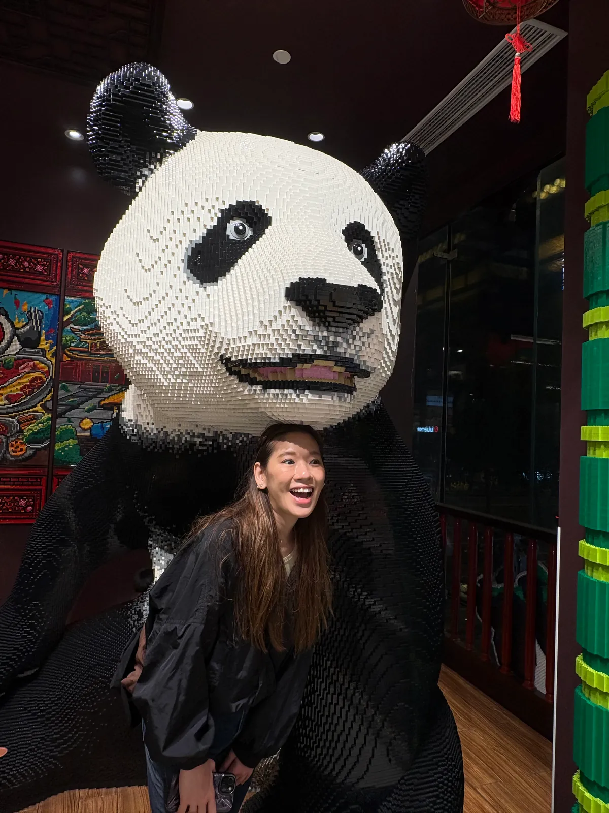 Woman posing beneath a giant brick-built panda