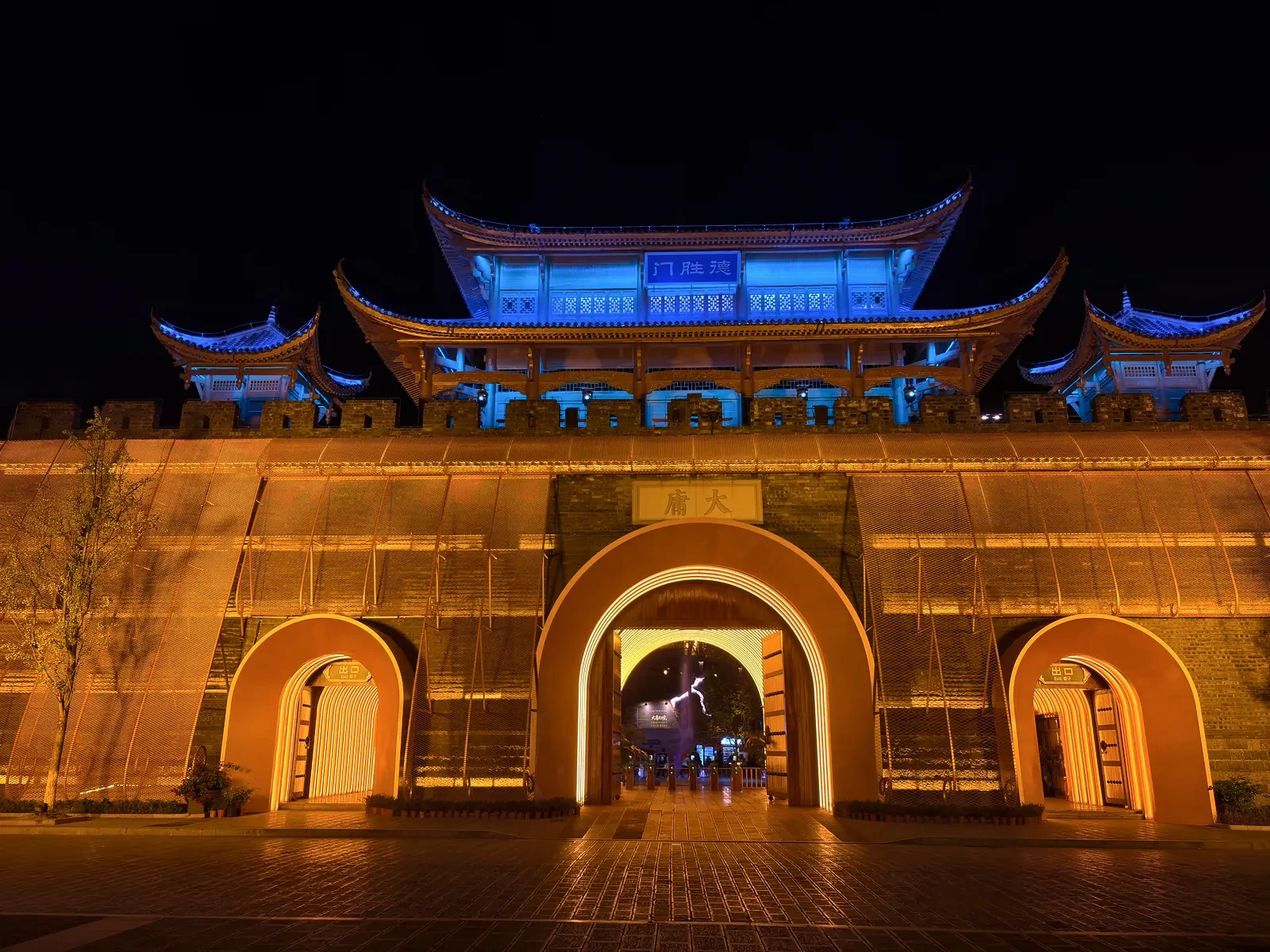Desheng Gate of Dayong Ancient City, its three arched doorways glowing amber under blue-lit roofs