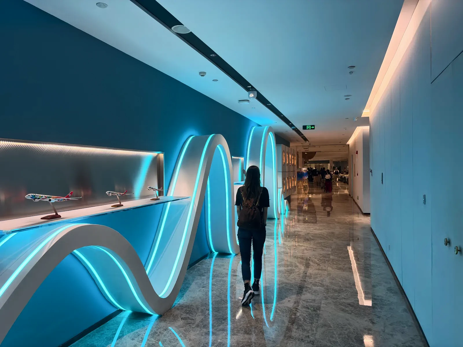 Woman walking through a blue-lit corridor at Tianfu Airport