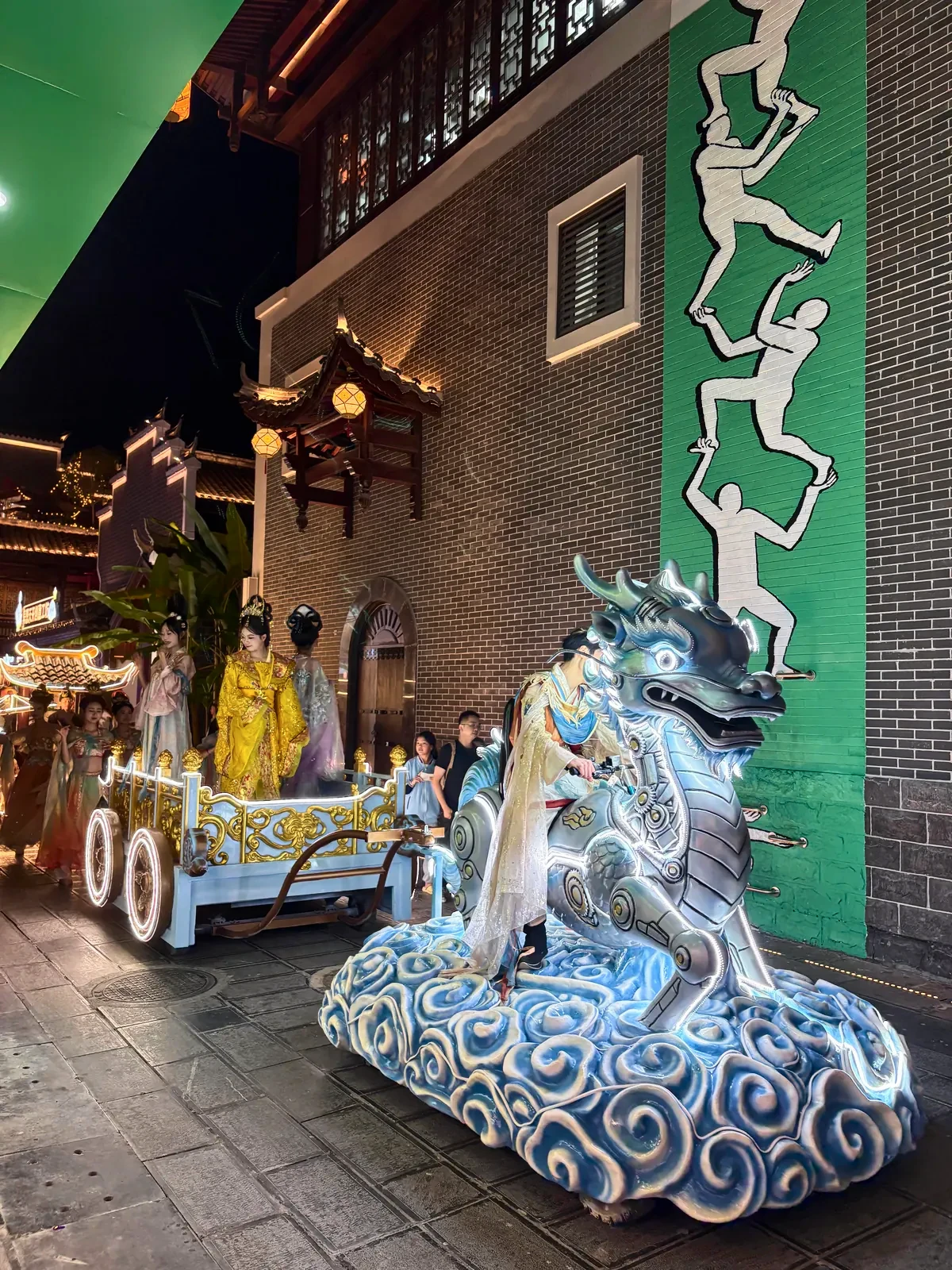 Illuminated qilin float with costumed performers in a street at night