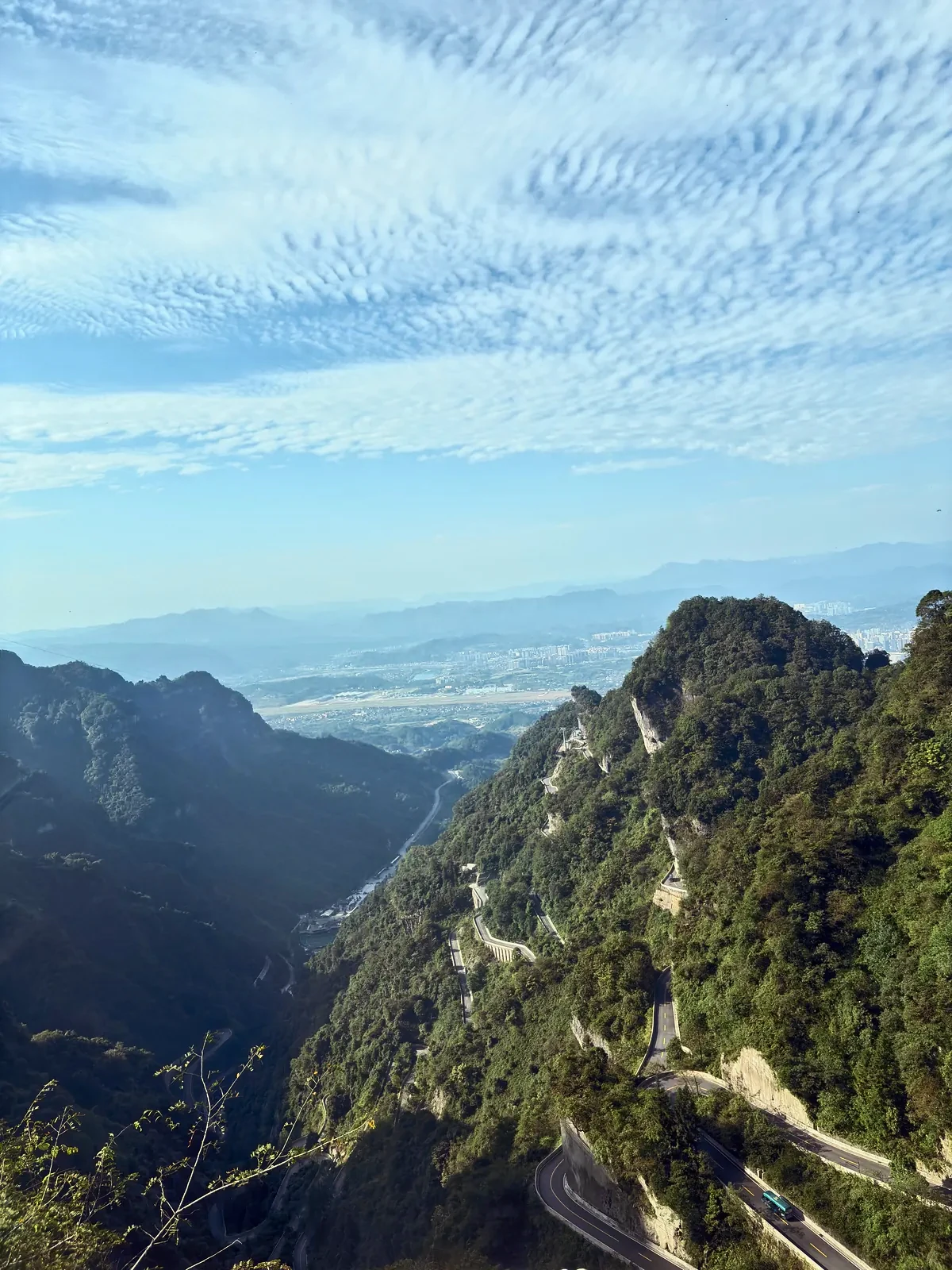 View from Tianmen Mountain down to the switchback road winding up the valley, beneath rippled clouds