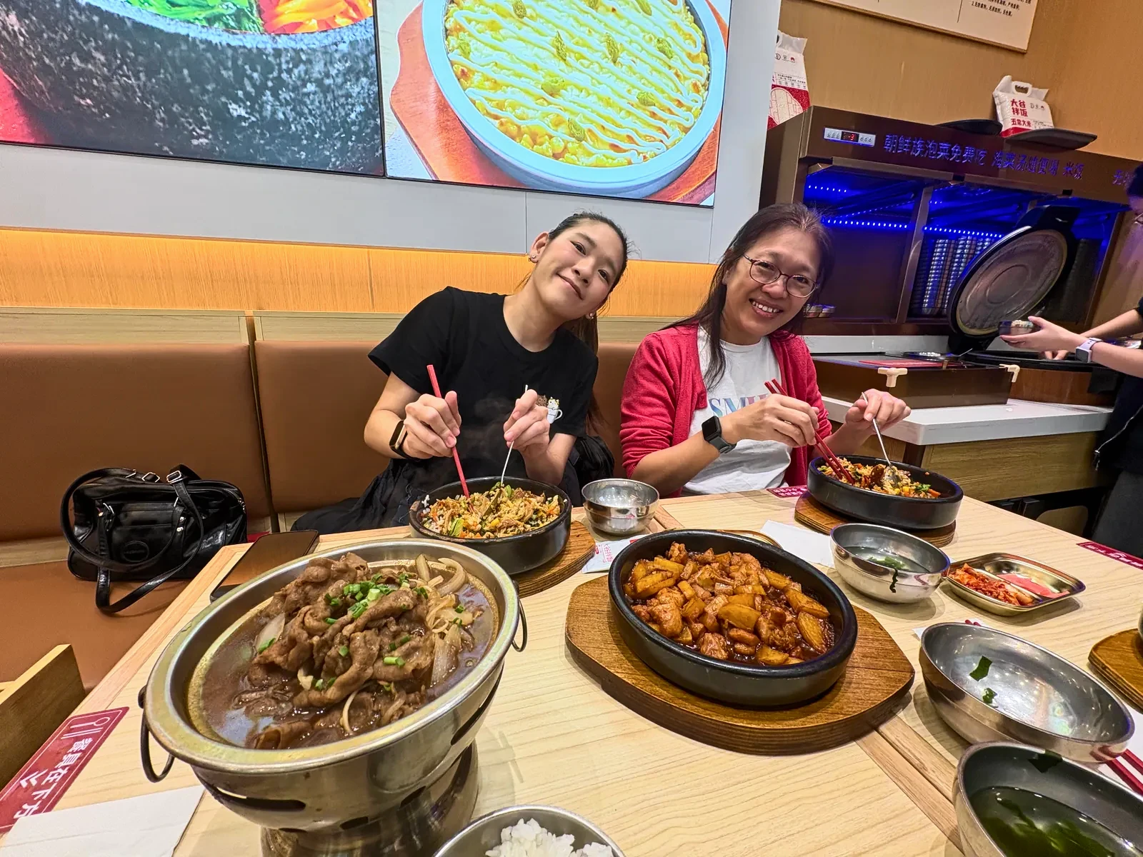 Mother and daughter sharing a Korean lunch of bulgogi, stone-pot bibimbap and braised potatoes
