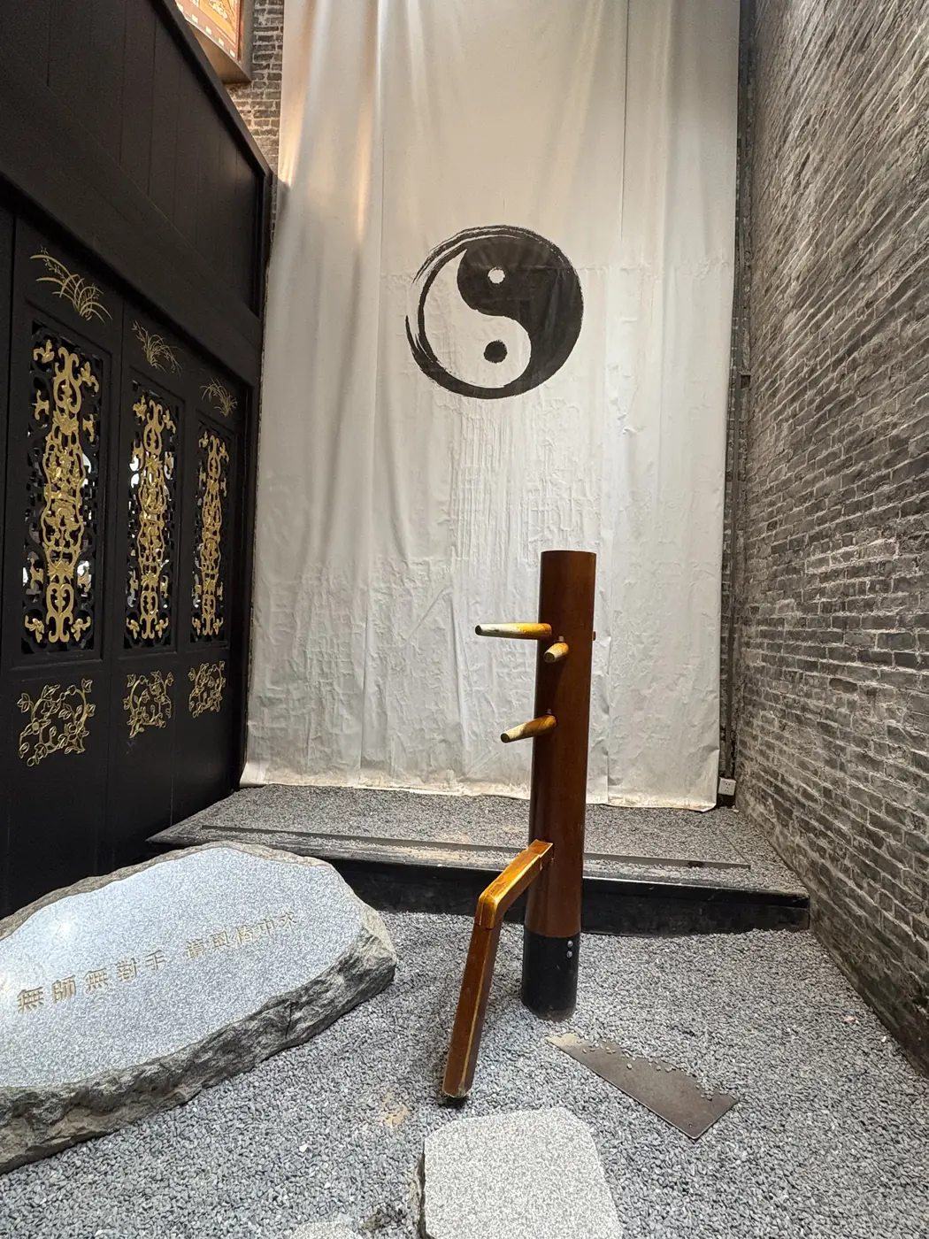 Wooden Wing Chun dummy in a traditional courtyard